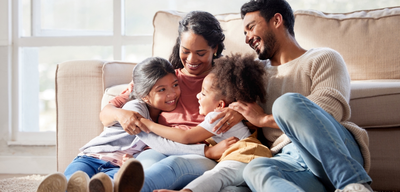Family huddled on a sofa smiling.